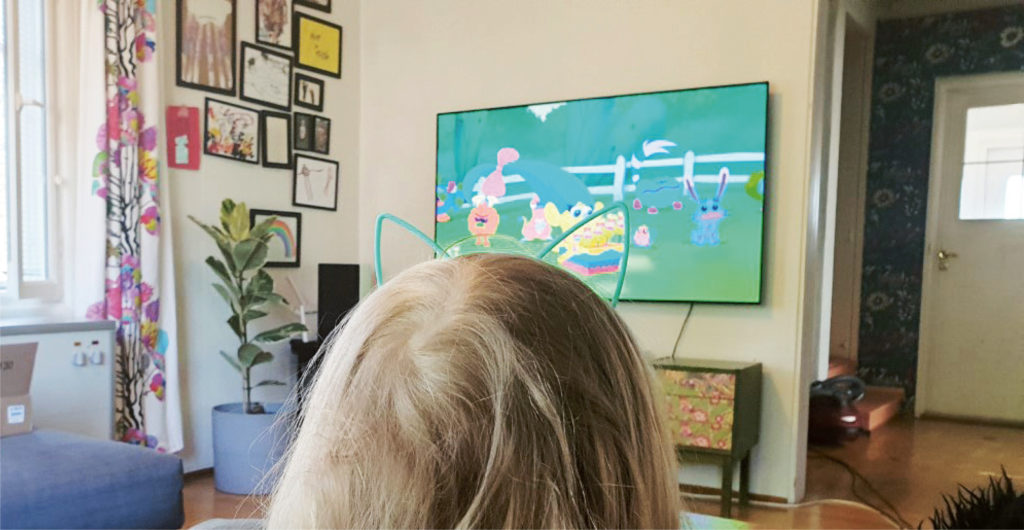 Kuvassa näkyy lapsen pää takaa ja edessä televisio. 