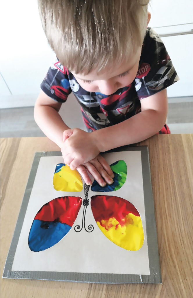 Sotkutonta maalausta. Lapsi ja sotkuttumalla maalaustekniikalla tehty perhonen.