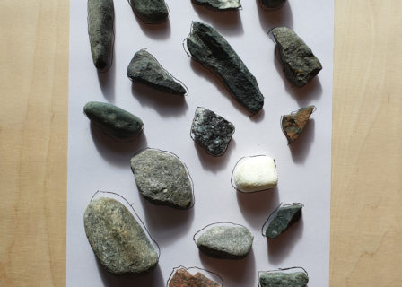 Kuvassa paperin päällä erilaisia kiviä.
