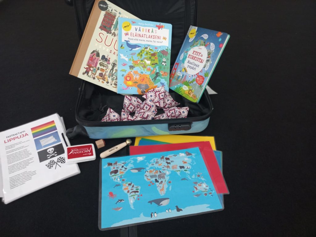 Kuvassa Bom Dia! -laukku jonka sisällä kirjoja, karttoja ja muuta materiaalia
