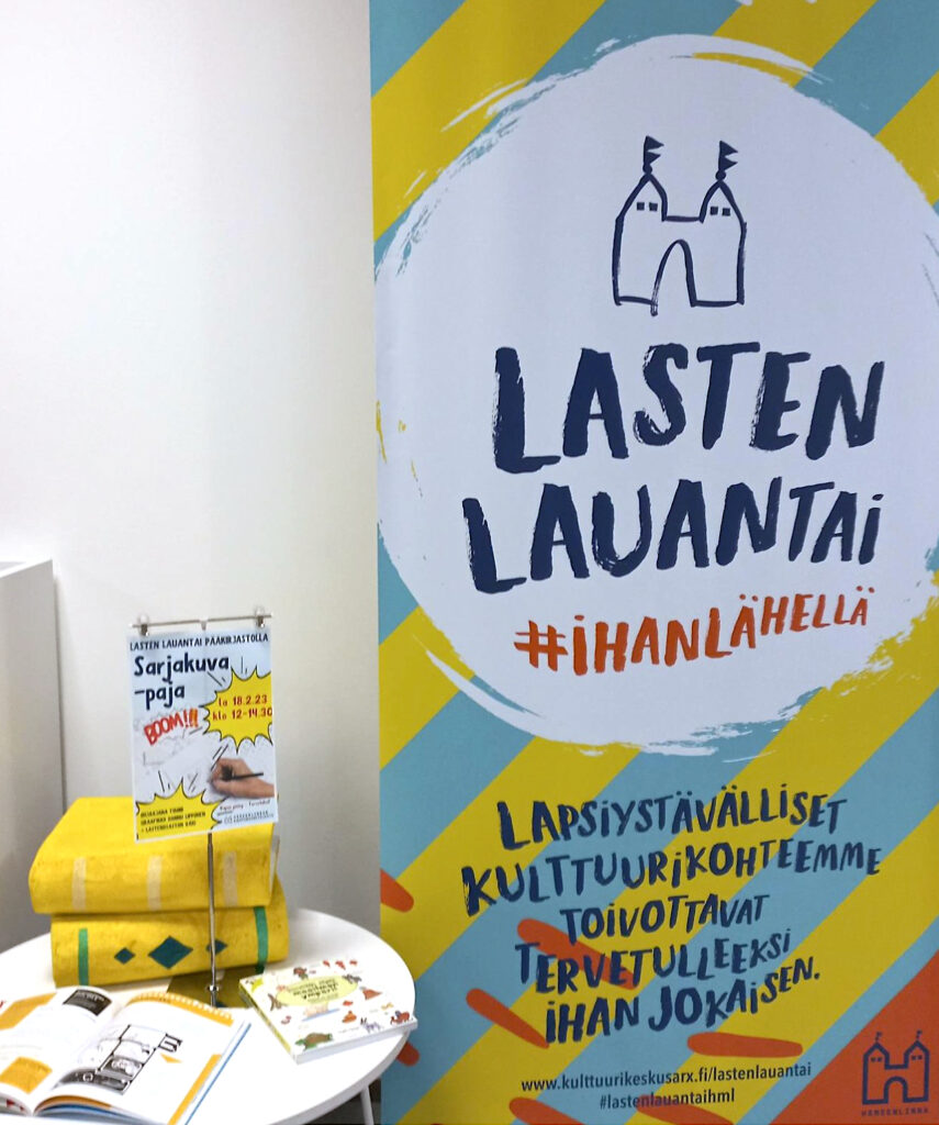 Lasten lauantain roll up-juliste ja mainos kirjastolla