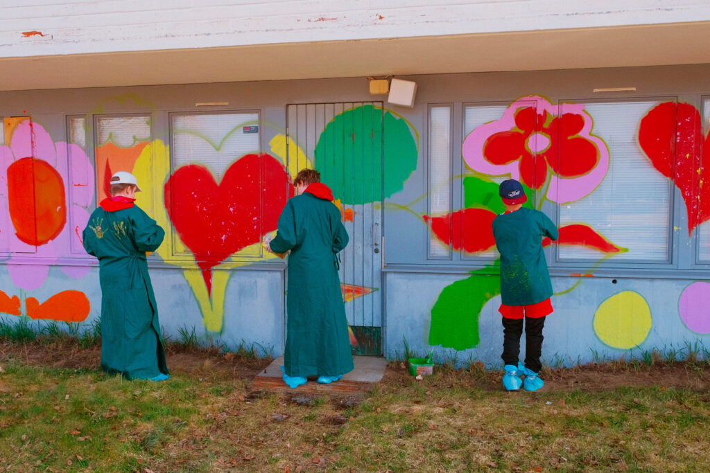 Räikee -katutaidefestivaalissa lapset ja nuoret tekevät graffiteja purkutaloihin.
