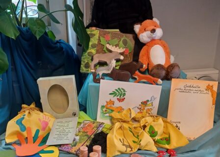 materiaaleja seikkailu luovuuteen -lainamateriaalista; Arsi-kettu-pehmo, kirjoja, pikkuleluja ja eläimiä, askelmia ja käden jälkiä, retkireppu