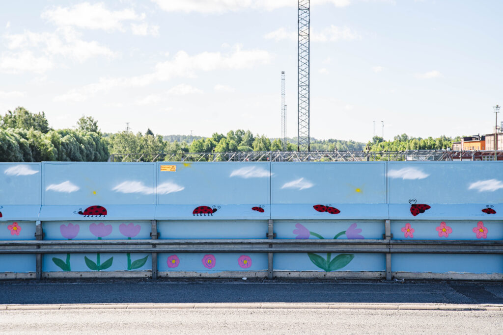 Maalattu kaide, maalauksessa taivas, leppäkerttuja ja kukkia