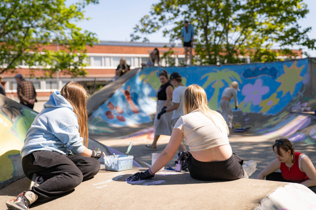Nuoret selät kameraan maalaavat skuuttipuistoa