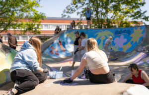 Nuoret selät kameraan maalaavat skuuttipuistoa