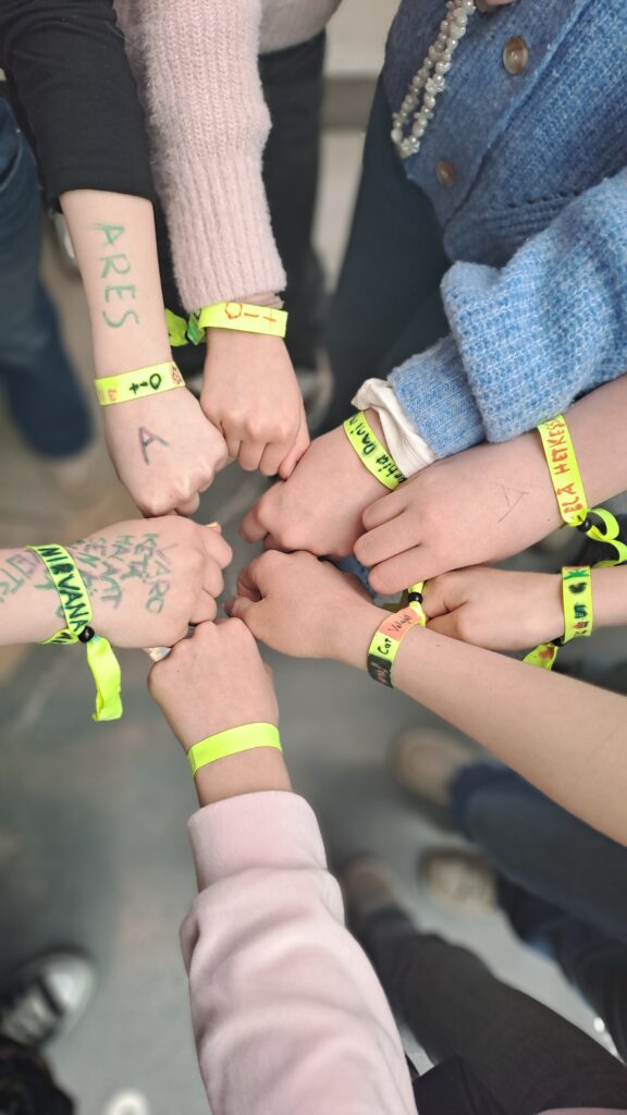 Lasten kädet ympyrässä. Käsissä keikkarannekkeet. 